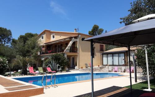 a house with a swimming pool and an umbrella at Les Gites du Mas des Cigales in Nîmes