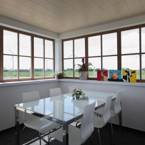 a dining room with a glass table and white chairs at B&B Back2Front in Boezinge