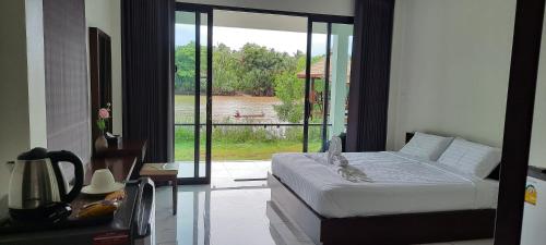 a bedroom with a bed and a view of a pool at Suan Son Villa Koh Sa Nher สวนสนธิ์วิลล่า เกาะเสนอ SHA in Surat Thani