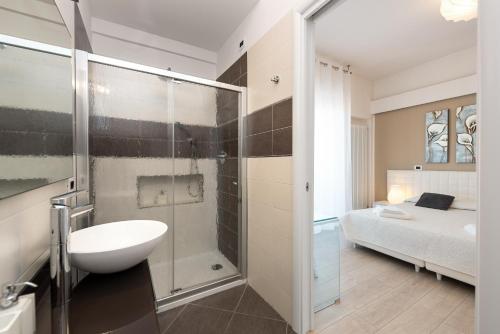 uma casa de banho com um lavatório, um chuveiro e uma cama. em Rosella Apartment em Verona