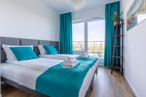 a bedroom with two beds and a large window at Symphony Baltica Towers Apartamenty in Gdańsk