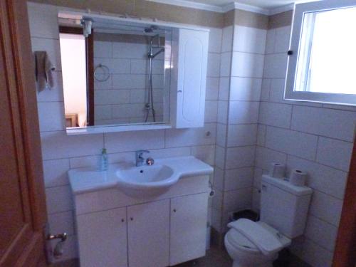 a bathroom with a sink and a toilet and a mirror at Katerinas Place in Analipsi