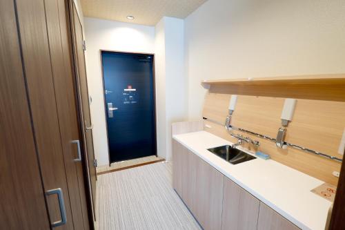 ein Badezimmer mit einem Waschbecken und einer blauen Tür in der Unterkunft Stay SAKURA Kyoto TSUBAKI in Kyoto