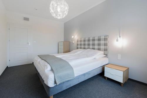 a bedroom with a large bed and a night stand at Symphony Baltica Towers Apartamenty in Gdańsk