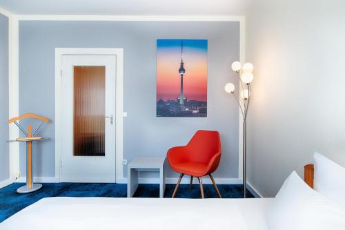 a bedroom with a red chair and a desk at Hotel Carolinenhof in Berlin