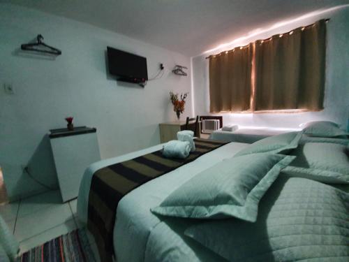 a hotel room with two beds and a television at Pousada Solar dos Cavaleiros Mendes in Macaé