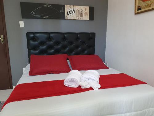 a bed with red pillows and towels on it at Pousada Solar dos Cavaleiros Mendes in Macaé