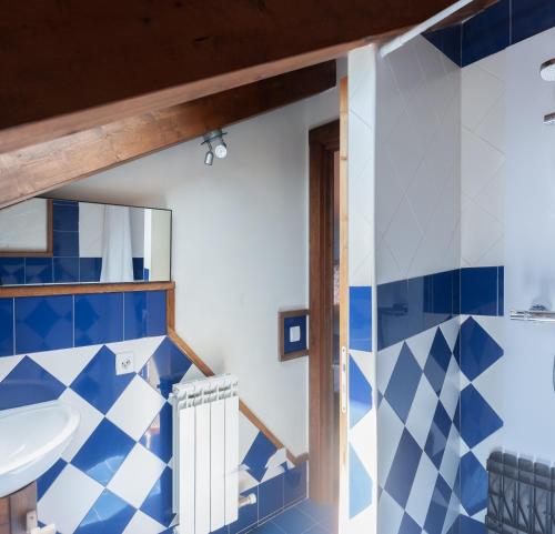 a bathroom with blue and white tiles and a sink at Albergue A'Noguera in Castiello de Jaca