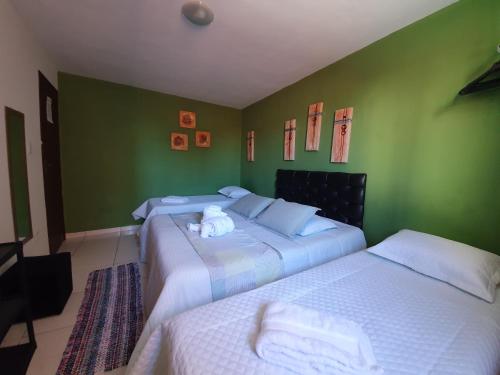 two beds in a room with green walls at Pousada Solar dos Cavaleiros Mendes in Macaé