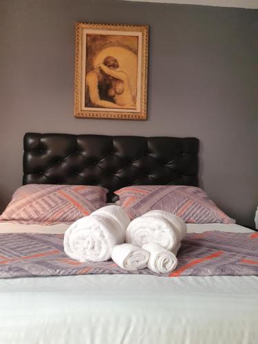 two towels on a bed with a picture on the wall at Pousada Solar dos Cavaleiros Mendes in Macaé