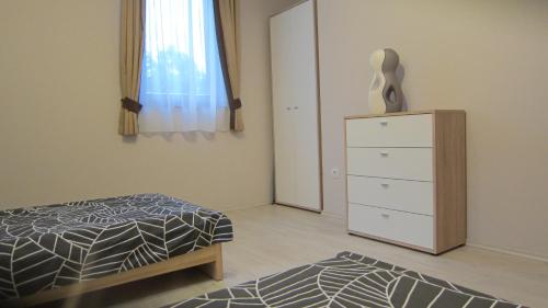 a bedroom with a bed and a dresser and a window at Appartment Kastelo Victoria in Zalacsány