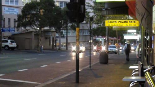 a street with cars driving down a city street at Central Private Hotel in Sydney