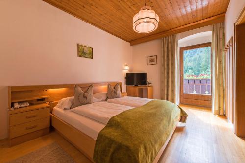 a bedroom with a large bed and a window at Alpin Natur Hotel Brückele in Braies