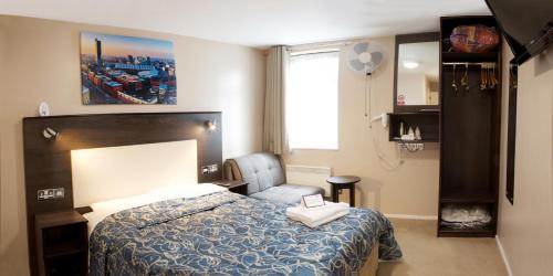 um quarto com uma cama, uma cadeira e uma janela em Stay Inn Manchester em Manchester