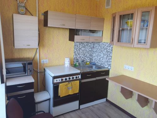 a small kitchen with a stove and a microwave at Apartament Erfolg 3 in Daugavpils