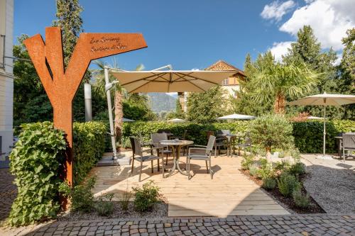 a patio with an umbrella and a table and chairs at Hotel Kolping in Merano