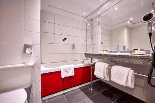 uma casa de banho com um lavatório vermelho e branco e uma banheira em Hotel Schillingshof em Bad Kohlgrub