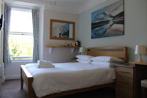 a bedroom with a bed with white sheets and a window at The Bay House Lake View Guest House - Adults Only in Bowness-on-Windermere