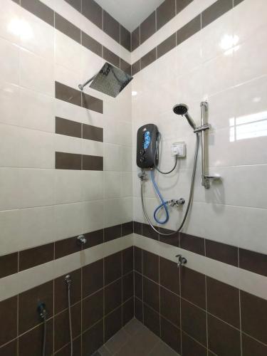 a shower in a bathroom with brown and white tiles at Ku's Roomstay in Pantai Cenang