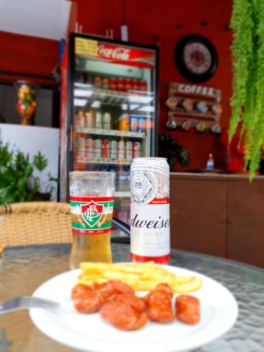 a table with a plate of food and a glass of beer at Pousada Solar dos Cavaleiros Mendes in Macaé