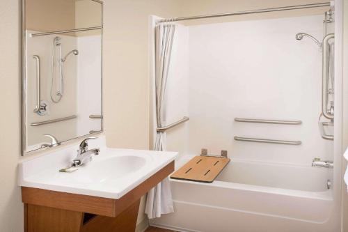 a bathroom with a sink and a tub and a shower at WoodSpring Suites Raleigh Northeast Wake Forest in Raleigh