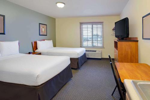 a hotel room with two beds and a flat screen tv at WoodSpring Suites Raleigh Northeast Wake Forest in Raleigh