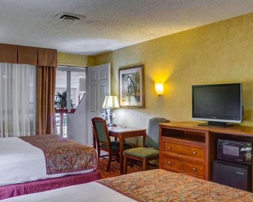 a hotel room with a bedroom with a television and a desk at Rodeway Inn Columbia Mall Loop in Grand Forks