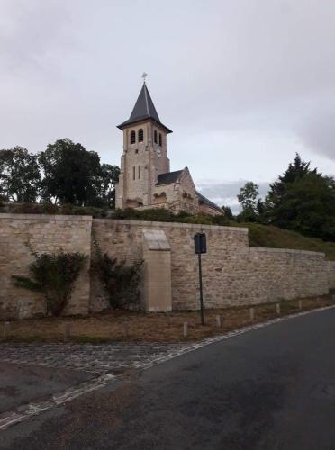 a building with a tower on top of a stone wall at La maison du colombophile in Neuville-sur-Ailette