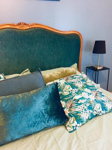 a bed with a green headboard and two pillows on it at La Longère du Salou in Landrévarzec