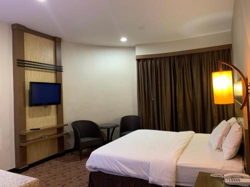a hotel room with a bed and a flat screen tv at Sento Hotel in Keningau