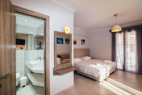 a bedroom with a bed and a sink and a mirror at Zen Apartments in Laganas