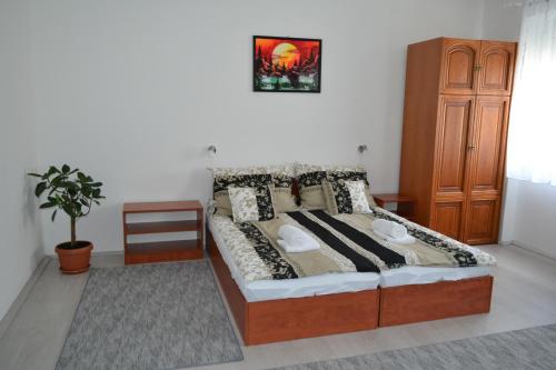 a bedroom with a bed and a wooden cabinet at Fészek Apartmanház in Tapolca