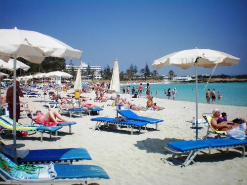 a group of people on a beach with chairs and umbrellas at 103 ELEGANT 2 bed apartment with free Wifi, AC, pool & gym! in Larnaka
