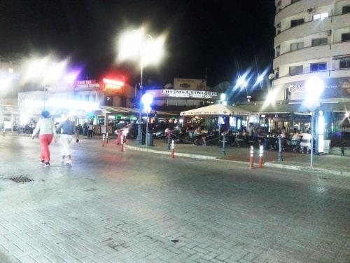 a group of people walking down a street at night at 103 ELEGANT 2 bed apartment with free Wifi, AC, pool & gym! in Larnaka