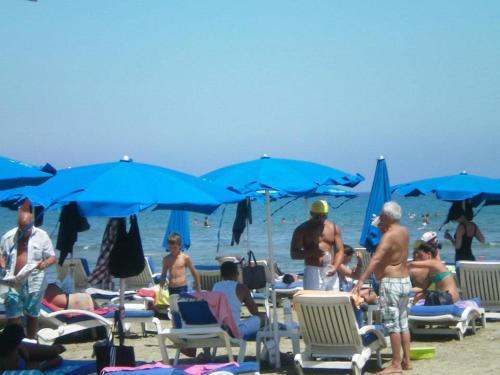 a group of people on a beach with blue umbrellas at 103 ELEGANT 2 bed apartment with free Wifi, AC, pool & gym! in Larnaka