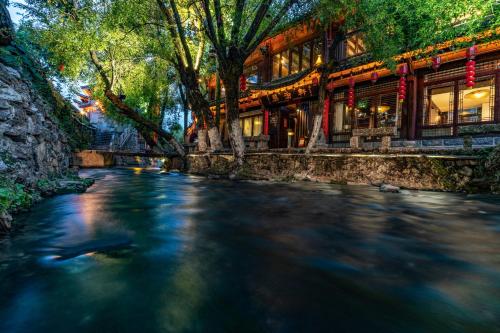 a river in front of a chinese building at Jun Bo Xuan Boutique Hotel in Lijiang