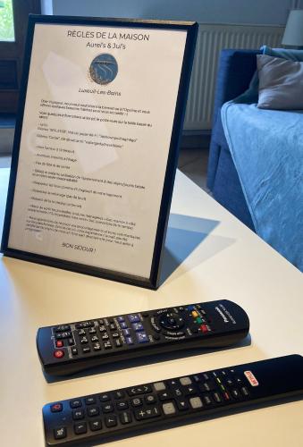 a sign and a remote control on a table at Aurel's & Jul's Location-Luxeuil Meublés pour Professionnels Curistes et Touristes in Luxeuil-les-Bains
