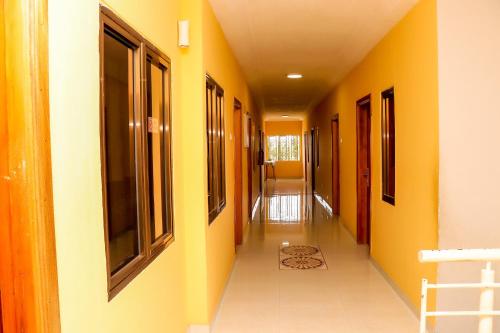 an empty hallway with yellow walls and a hallway with windows at Bonsukoda Lodge in Accra