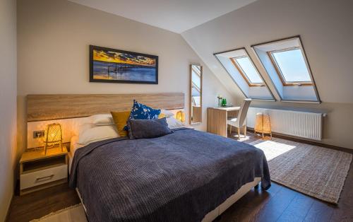 a bedroom with a bed and a desk and windows at Vitis Kúria 7171 Balatonrendes in Balatonrendes