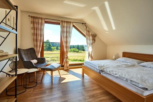 a bedroom with a bed and a chair and a window at Chalupa pod Plešivcem in Abertamy