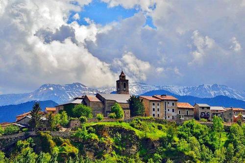 un edificio en una colina con montañas en el fondo en Ático con encanto en Bellver de Cerdanya, en Bellver de Cerdanya 