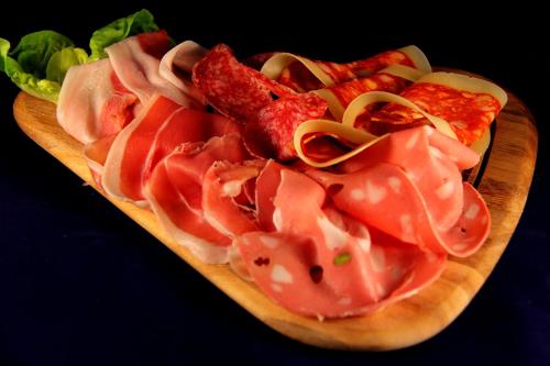 a plate of meat and bacon on a cutting board at La Favorita Apricale B&B & Ristorante in Apricale