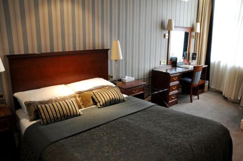 a hotel room with a large bed and a desk and a desk at Cairn Hotel in Harrogate