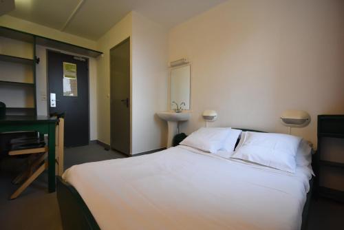 - une chambre avec un grand lit blanc et un lavabo dans l'établissement Auberge de Jeunesse HI Paris Le d'Artagnan, à Paris