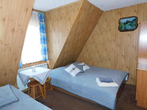ザコパネにあるPokoje Gościnne Monikaのベッド2台、テーブル、ベッド1台が備わる客室です。
