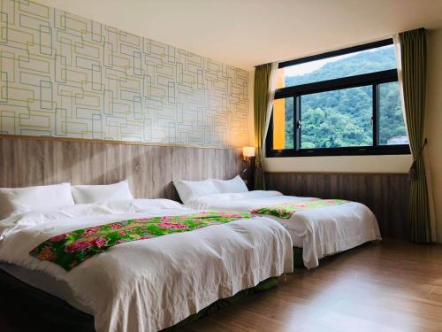 two beds in a room with a large window at 南庄漫晨旅店Nanzhuang Manchen B&B in Nanzhuang
