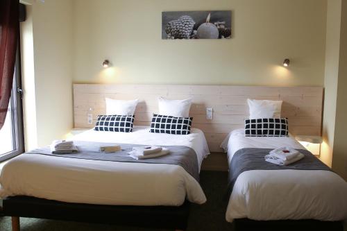 two beds in a hotel room with towels on them at Hôtel La Couronne in Marmande
