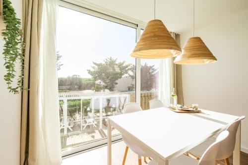 a dining room with a white table and a large window at Casa Vica - Sagres Apartments in Sagres