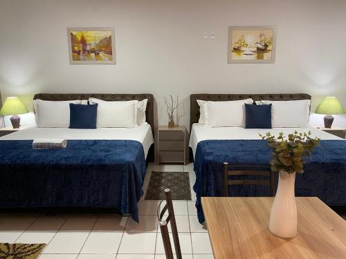 a hotel room with two beds and a table at B & A Suites Inn Hotel - Quarto Luxo Safira in Anápolis