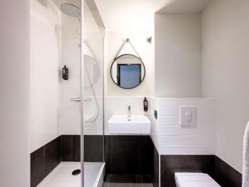 uma casa de banho com um chuveiro, um lavatório e um espelho. em ibis La Rochelle Vieux Port em La Rochelle